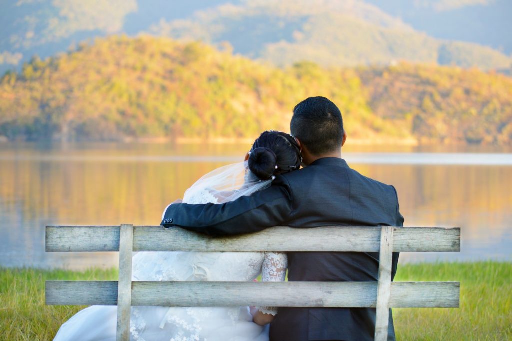 Bride and groom on bench during the fall season